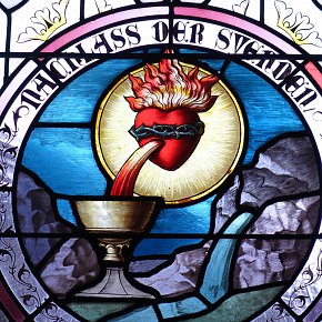 Warth, Pfarrkirche Hl. Sebastian, Herz mit Dornenkrone, Blutstrahl in Kelch, Wasser springt aus dem Felsen, Symbol für das Blut Christi als Quell des ewigen Lebens, Schrift: Nachlass der Sünden, 1895, Tiroler Glasmalerei